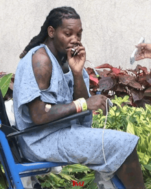 a man in a hospital gown is sitting in a wheelchair and smoking a cigarette