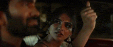 a man and a woman are sitting in a car at night . the woman is wearing earrings and a necklace .