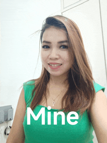 a woman wearing a green top with the word mine on the bottom