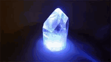 a crystal with a blue light coming out of it is glowing in the dark .