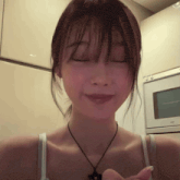 a woman with her eyes closed wearing a necklace