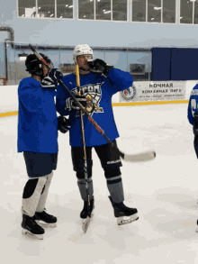 two ice hockey players on the ice with a sign in the background that says " ночная хоккейная лига "