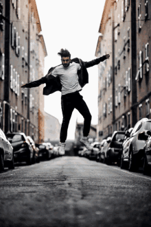 a man in a white shirt is jumping in the air between two buildings