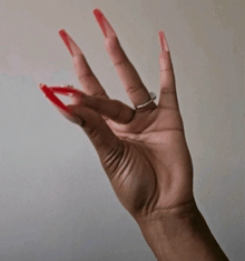 a woman 's hand with red nails and a silver ring