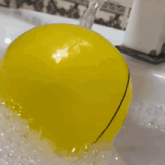 a yellow ball with a smiley face drawn on it sits in a bathtub
