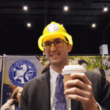 a man wearing a hard hat is holding a cup of coffee in front of a banner that says the crown college