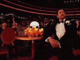 a man in a tuxedo is covering his face