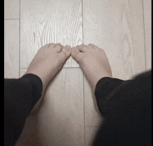 a person 's feet on a wooden floor with their toes crossed