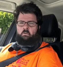 a man with glasses and a beard wears an orange shirt that says ' row ' on the front