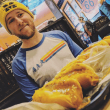 a man wearing a yellow hat with the word eye on it stands in front of a tray of food