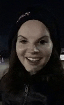 lana del rey is wearing a black hat and smiling .