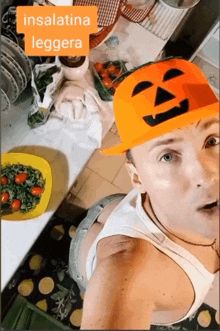 a man wearing an orange hat with a pumpkin face on it is standing in front of a kitchen counter