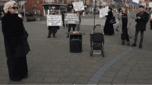 a woman stands in front of a group of protesters holding signs that say being a woman is not a hate crime