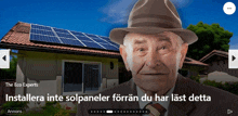 a man wearing a hat is in front of a house with solar panels on it