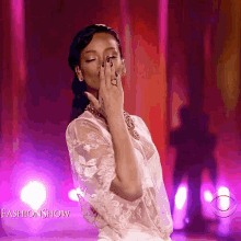 a woman covering her face with her hand while wearing a white lace top with the words fashion show on the bottom