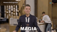 a man in a suit and tie is standing in a kitchen and says magia