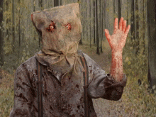 a scarecrow with a bag on his head is waving in the woods