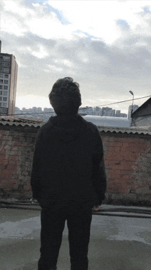 a man in a black hoodie stands in front of a building