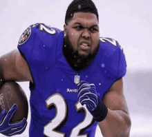 a man wearing a ravens jersey holds a football
