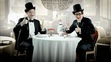two men in top hats are sitting at a table with a white table cloth