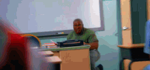 a man with blood on his face sits at a desk in front of a white board in a classroom