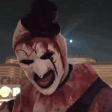 a bloody clown with a top hat is standing in front of a mcdonalds sign