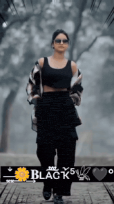 a woman wearing sunglasses and a black tank top is walking down a path with the words black 5 written below her