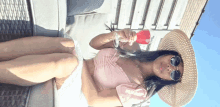 a woman wearing a hat and sunglasses is holding a glass of red wine