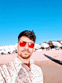 a man wearing red sunglasses takes a picture of himself on the beach