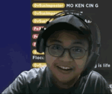 a boy wearing glasses and headphones is smiling in front of a screen that says mo ken cin g.