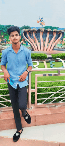 a man in a blue shirt stands in front of a statue of a cobra