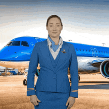 a woman in a blue uniform stands in front of a blue airplane with the letters nb on the side