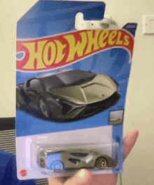 a person is holding a hot wheels toy car