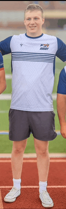 a man wearing a navy rugby shirt and shorts