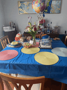 a happy birthday balloon hangs over a table with plates of food