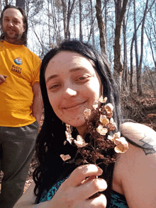 a man wearing a yellow shirt that says blood warrior is standing next to a woman holding flowers