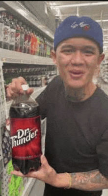 a man is holding a bottle of dr. thunder soda in a store .