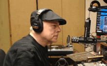 a man wearing headphones and a hat is sitting in front of a computer