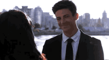 a man in a suit and tie is smiling and looking at a woman .