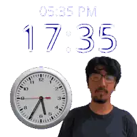 a man wearing glasses stands in front of a clock that says 17:35