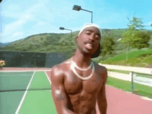 a shirtless man is standing on a tennis court wearing a headband .