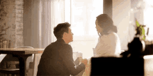 a man and woman are sitting at a table holding hands .