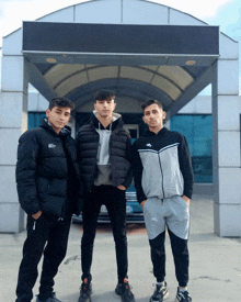 three young men pose for a picture in front of a building with a sign that says ' a ' on it