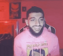 a man with a beard is wearing a pink hoodie .