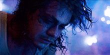 a man with curly hair looks down at something