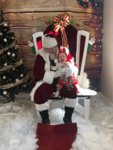 a baby is crying while sitting on santa 's lap in front of a christmas tree