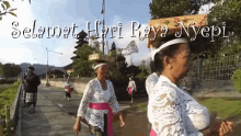 a group of women are walking down a street with the words " selamat hari raya nyepi " written above them