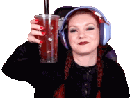 a woman wearing headphones is holding a cup of red liquid with a straw