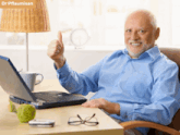 a man is giving a thumbs up in front of a laptop