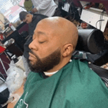 a bald man with a beard is sitting in a barber chair .